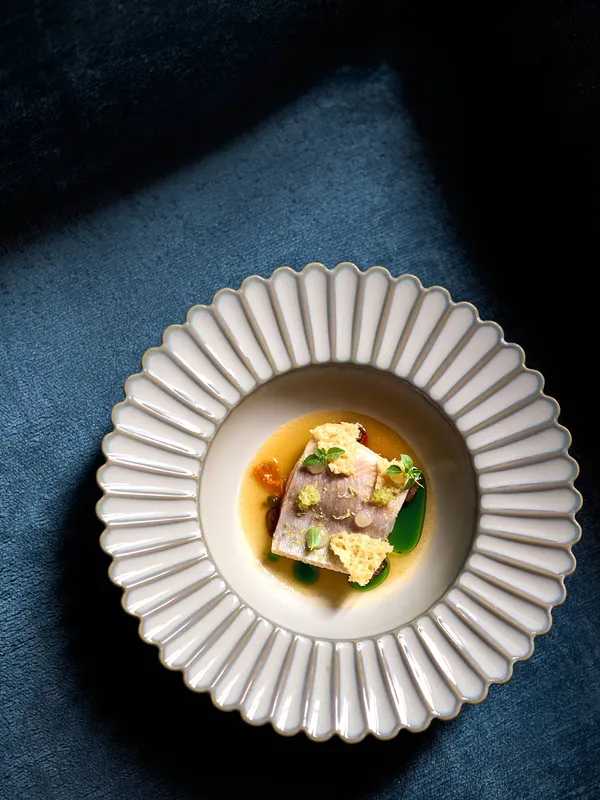 Gourmet-Fischgericht mit Microgreens und Sauce auf einem dekorativen weißen Teller